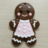 Adorno de galleta de jengibre marrón chocolate con vestido rosa y glaseado blanco