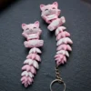 Pareja de llaveros gato articulado rosa y blanco sobre pizarra, uno con anilla