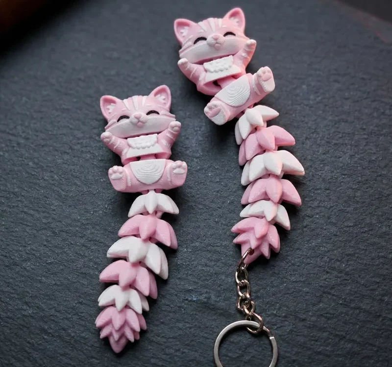 Pareja de llaveros gato articulado rosa y blanco sobre pizarra, uno con anilla
