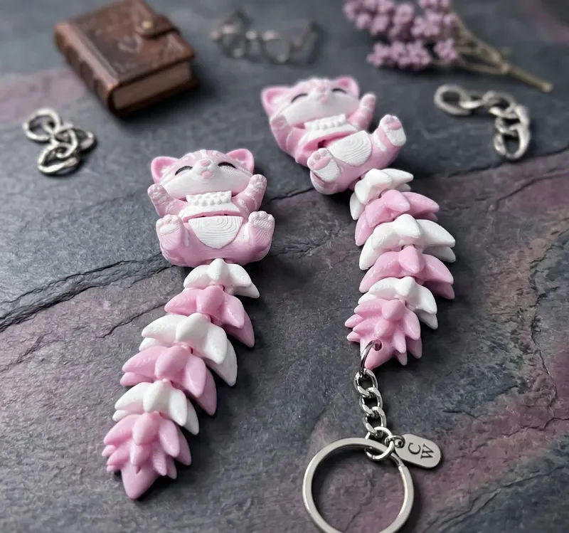 Dos llaveros gato flexi rosa y blanco con anillas y cadenas alrededor