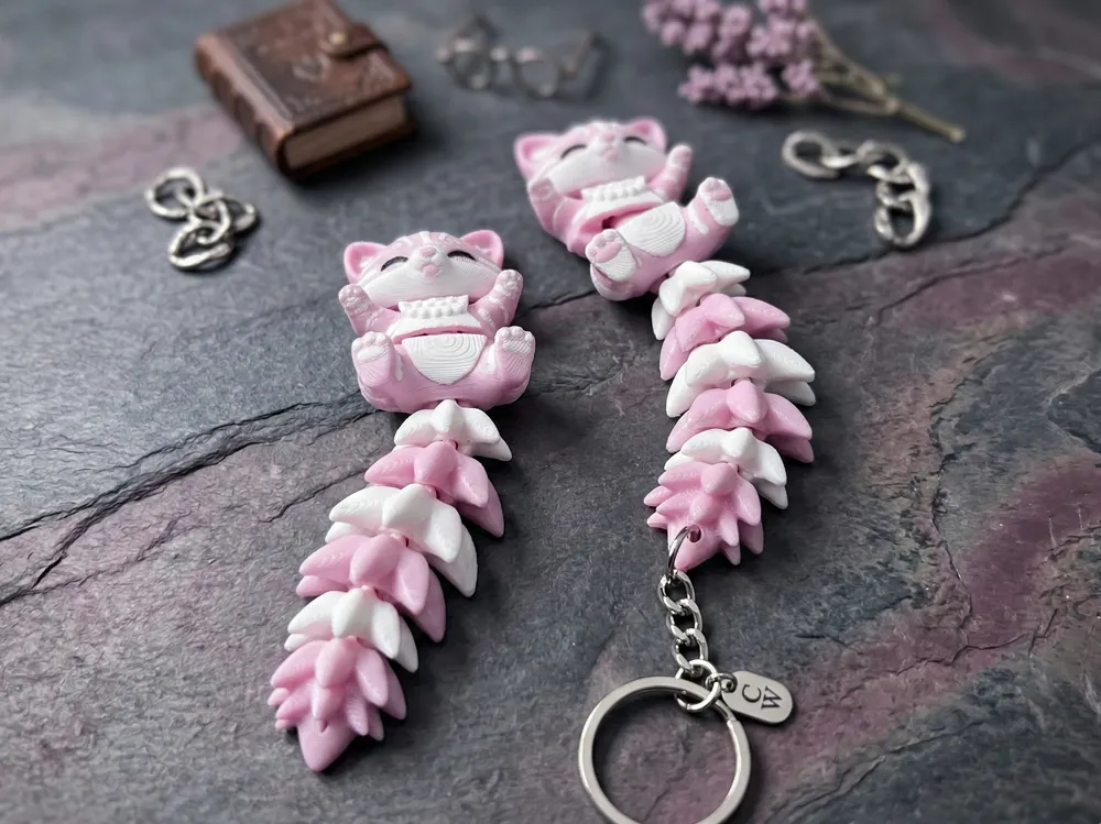 Dos llaveros gato flexi rosa y blanco con anillas y cadenas alrededor