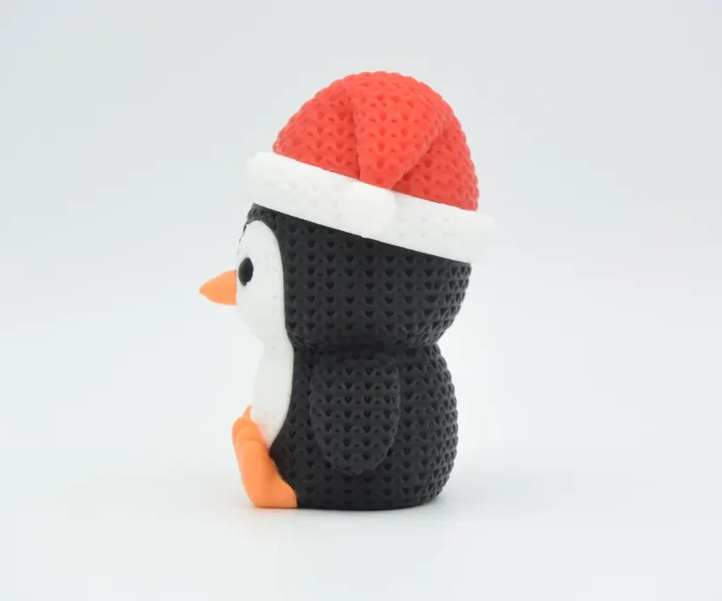 Pingüino navideño de punto visto de perfil, con pico y patas naranjas
