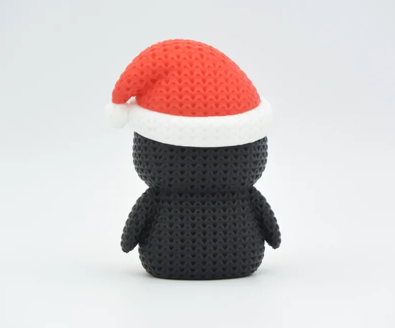Pingüino navideño de punto visto de espaldas, con gorro rojo y pompón blanco